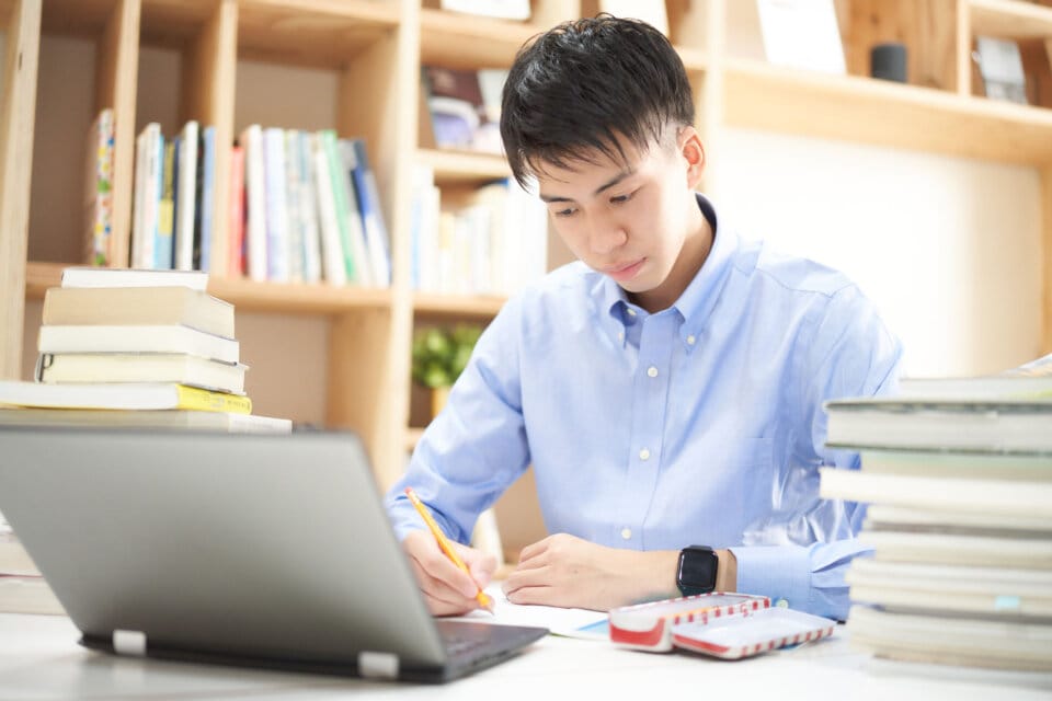 ノートパソコンを開いて勉強する男性の写真